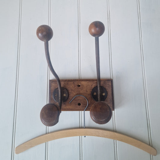 Wooden wall hook with wooden hooks on a white wooden panel