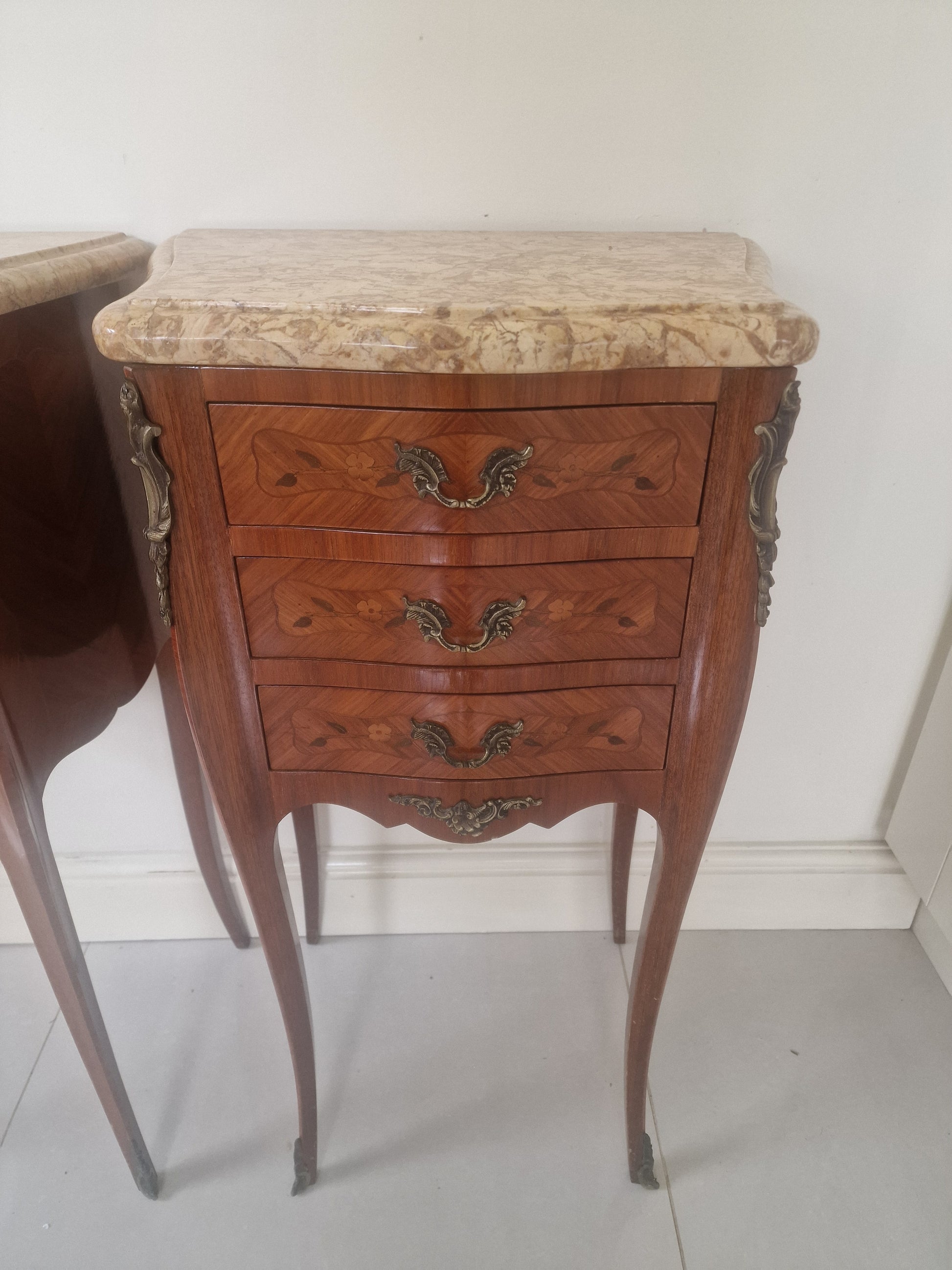 French Louis XV style wooden nightstand with marble top on a plain background