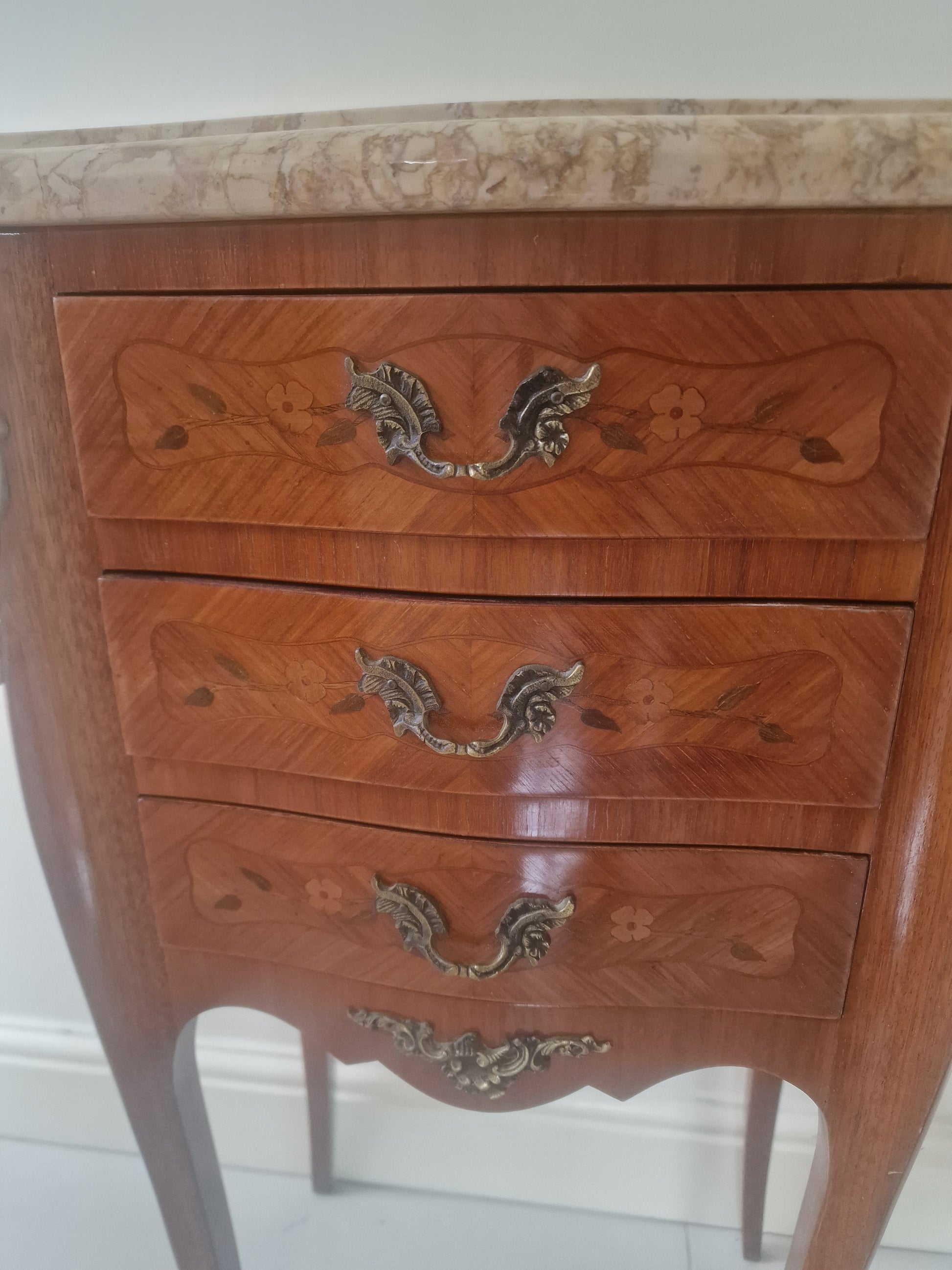 Pair of French Louis XV style wooden nightstands with marble tops on a plain background