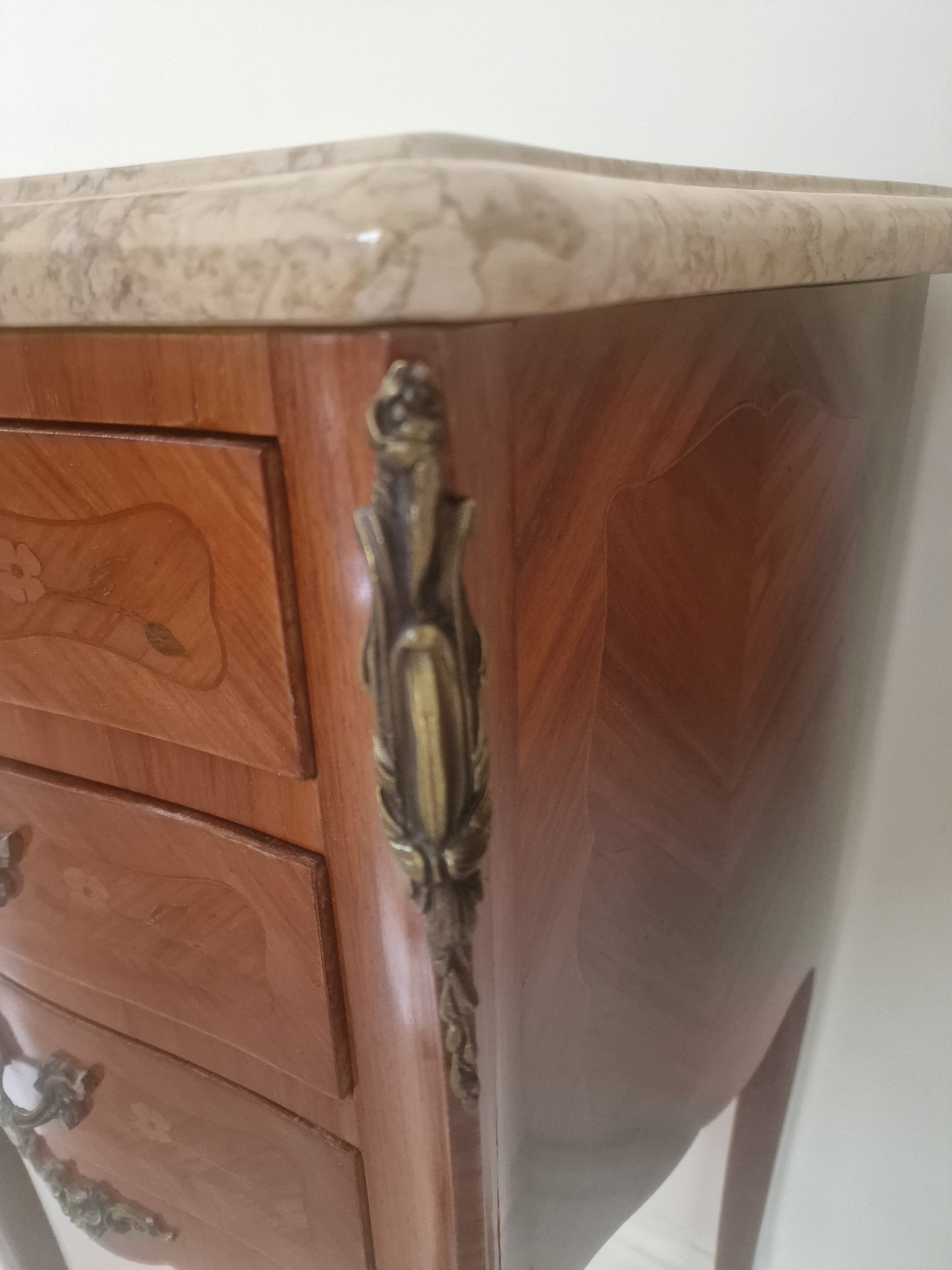 Corner of  Louis XV style wooden nightstand with marble top on a plain background
