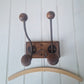 Wooden wall hook with wooden hooks on a white wooden panel 