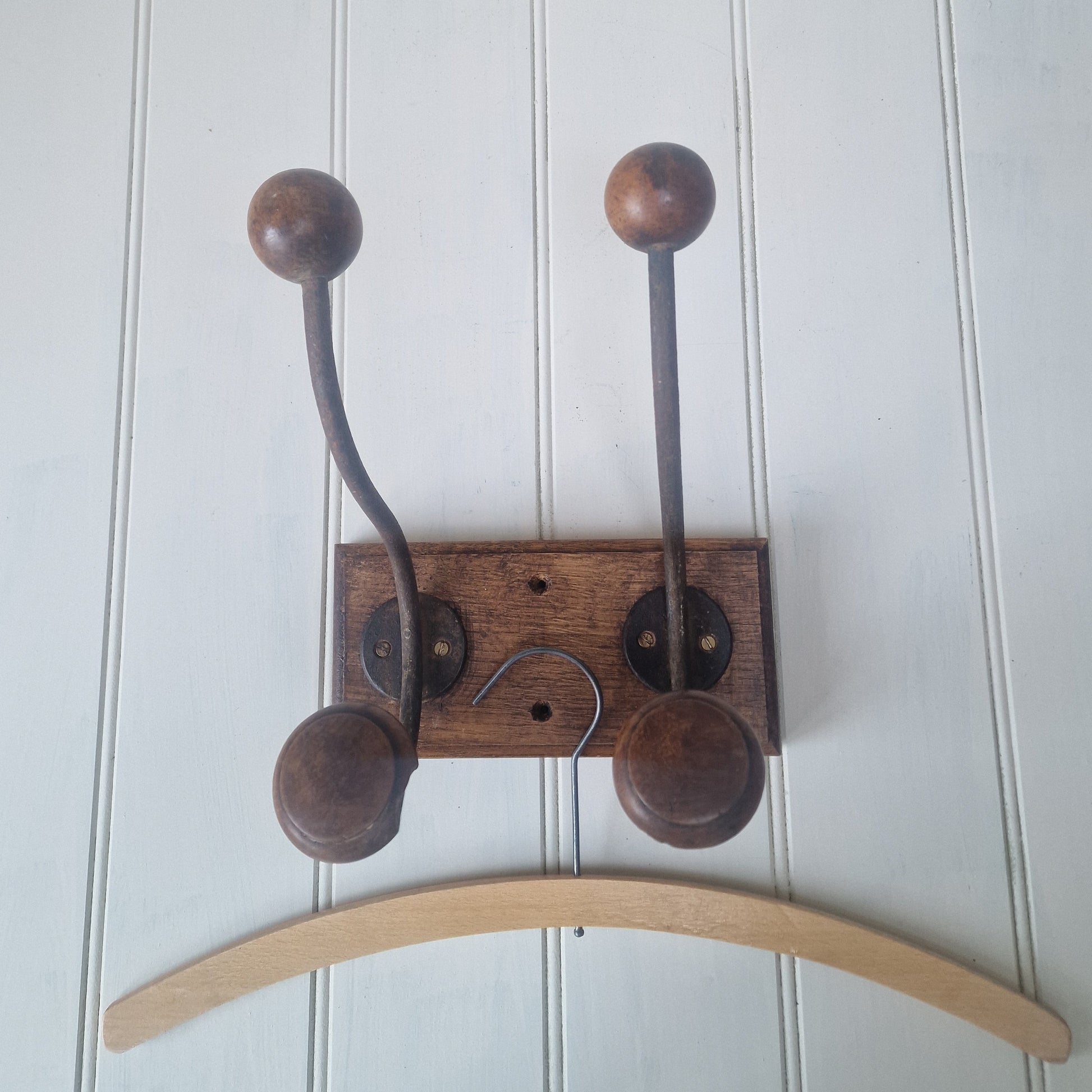 Wooden wall hook with wooden hooks on a white wooden panel 