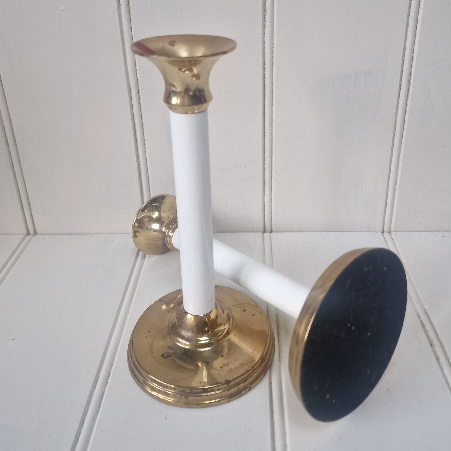 Two brass and white design candlesticks on a panelled table