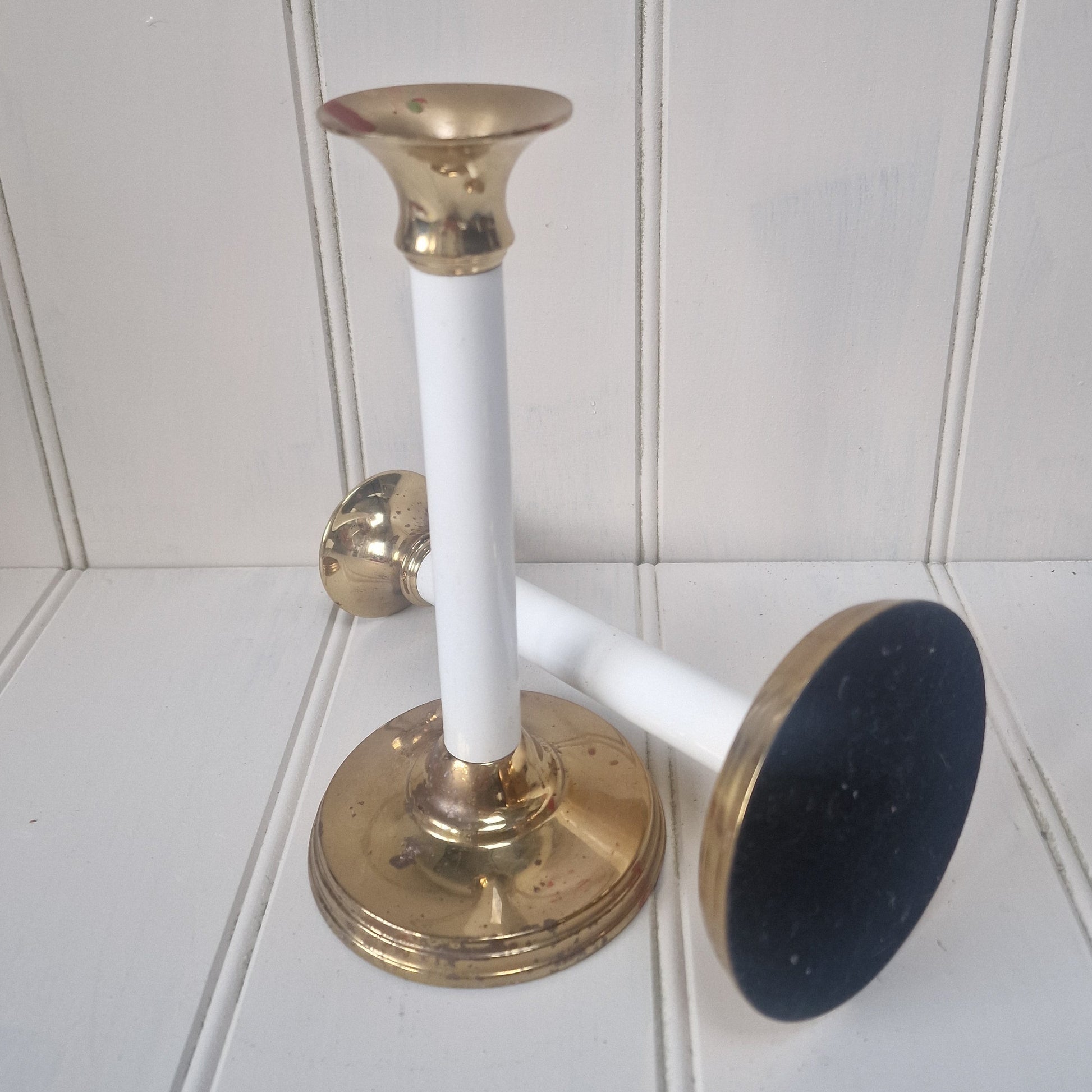 Two brass and white design candlesticks on a panelled table