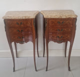 Pair of French Louis XV style wooden nightstands with marble tops on a plain background